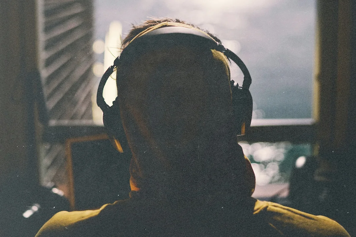 Man sitting on his balcony with headphones on, depicting a man Hearing from God