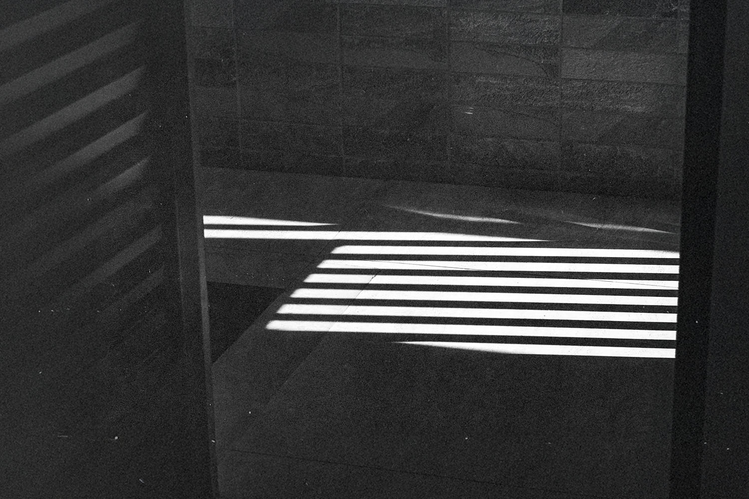 Bright horizontal light beams creating striped shadows across a tiled floor and wall