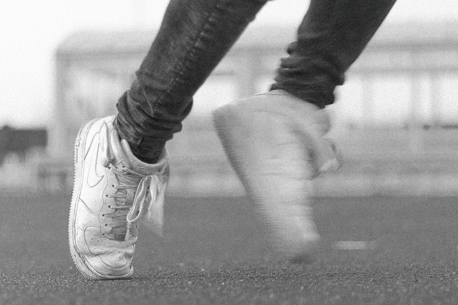 Close-up of a person in motion wearing worn sneakers on an outdoor track