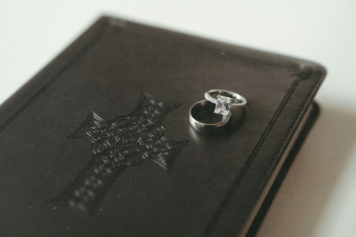 Wedding rings resting on top of a closed leather Bible embossed with a decorative cross