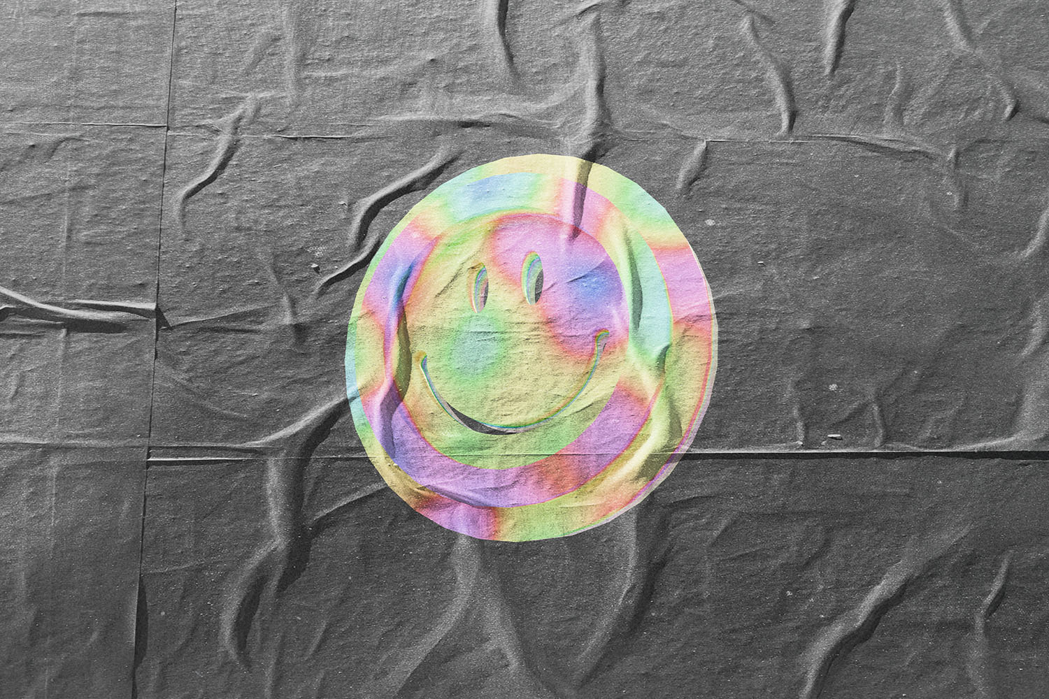 A colorful, iridescent smiley face graphic printed on a wrinkled dark fabric background