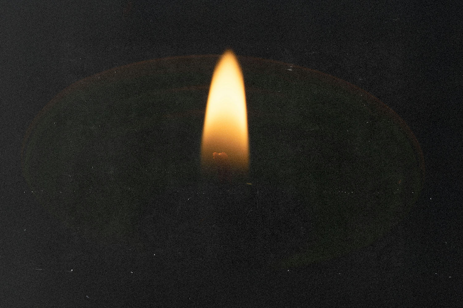 Single flame flickering in the dark, casting a soft glow