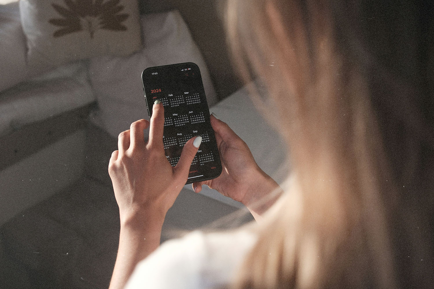 A person uses a smartphone, tapping on a full-year calendar displayed on the screen