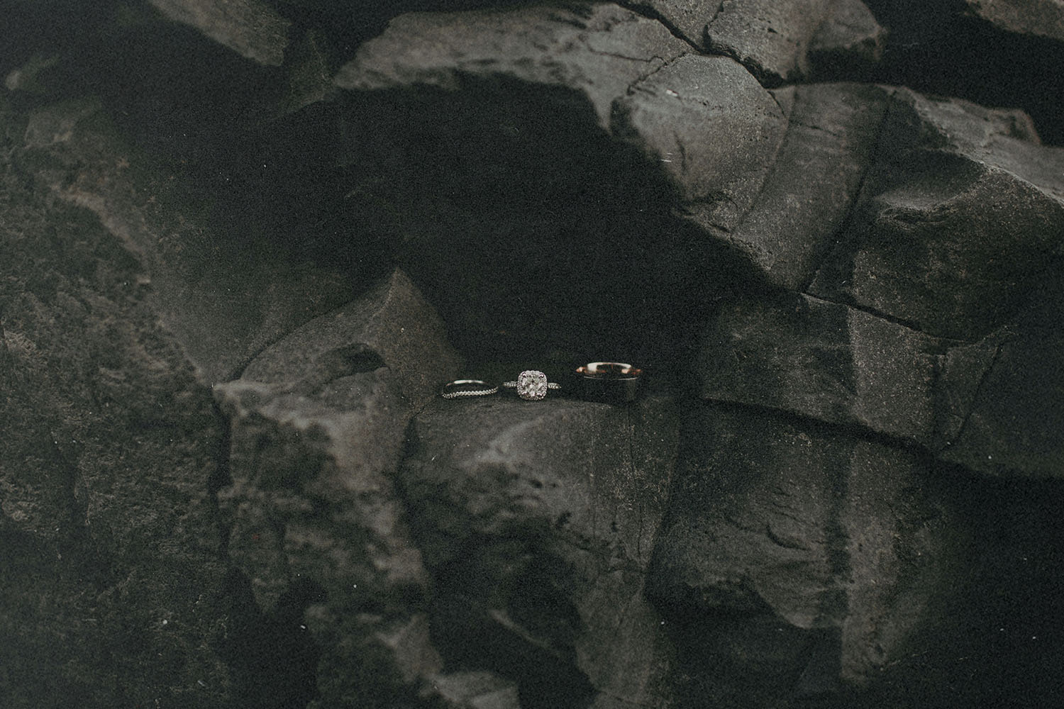 Two wedding rings resting on dark, textured volcanic rocks