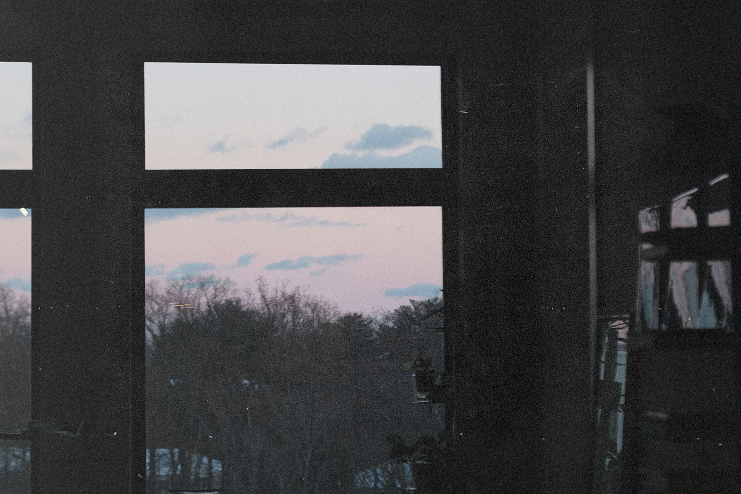 oft pink and blue sunset sky visible through a large window framing distant treetops