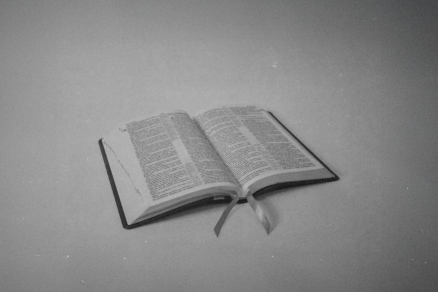 Open Bible resting on a flat surface with ribbon markers lying across the pages