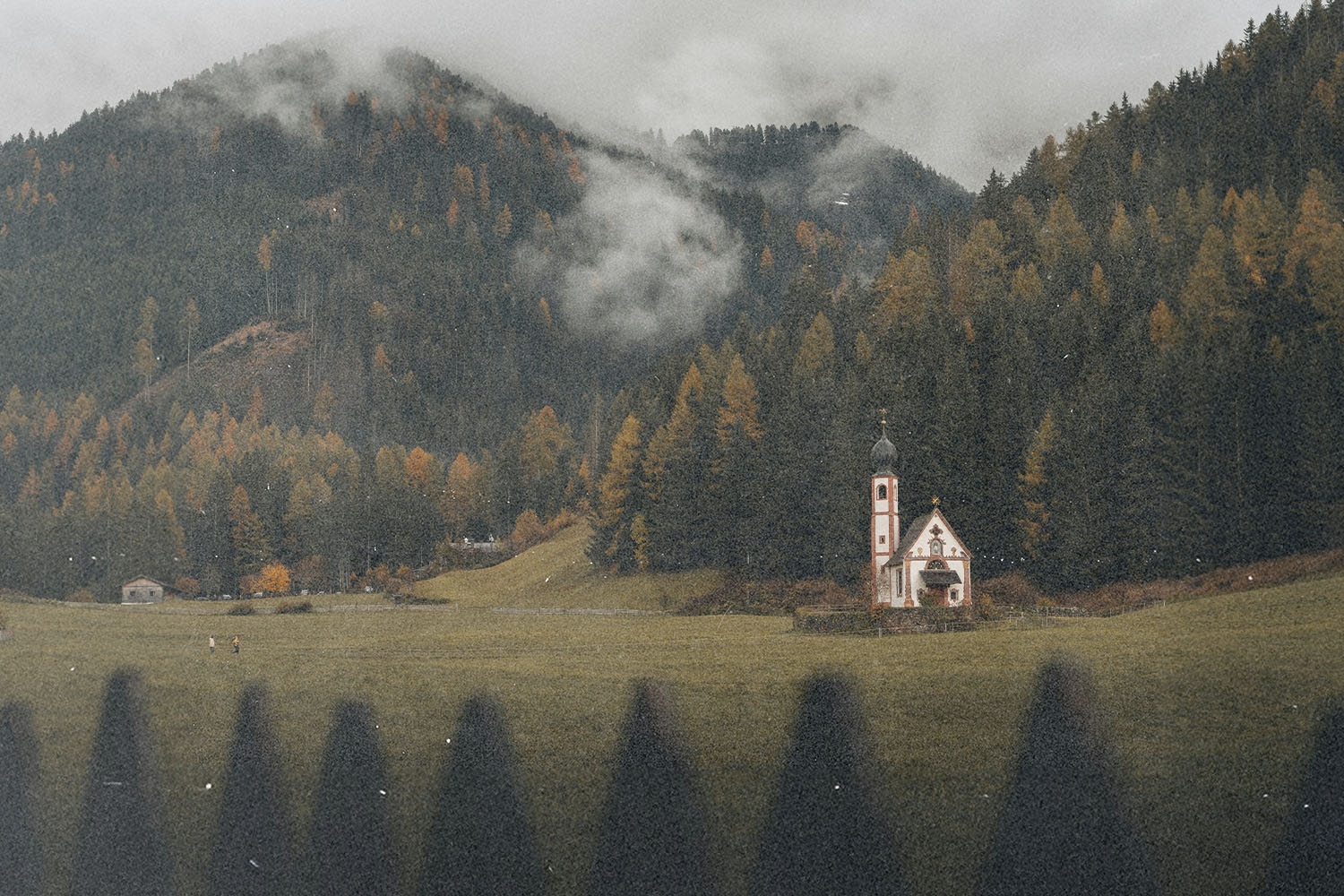 Small countryside chapel set in a misty mountain valley surrounded by dense autumn trees.