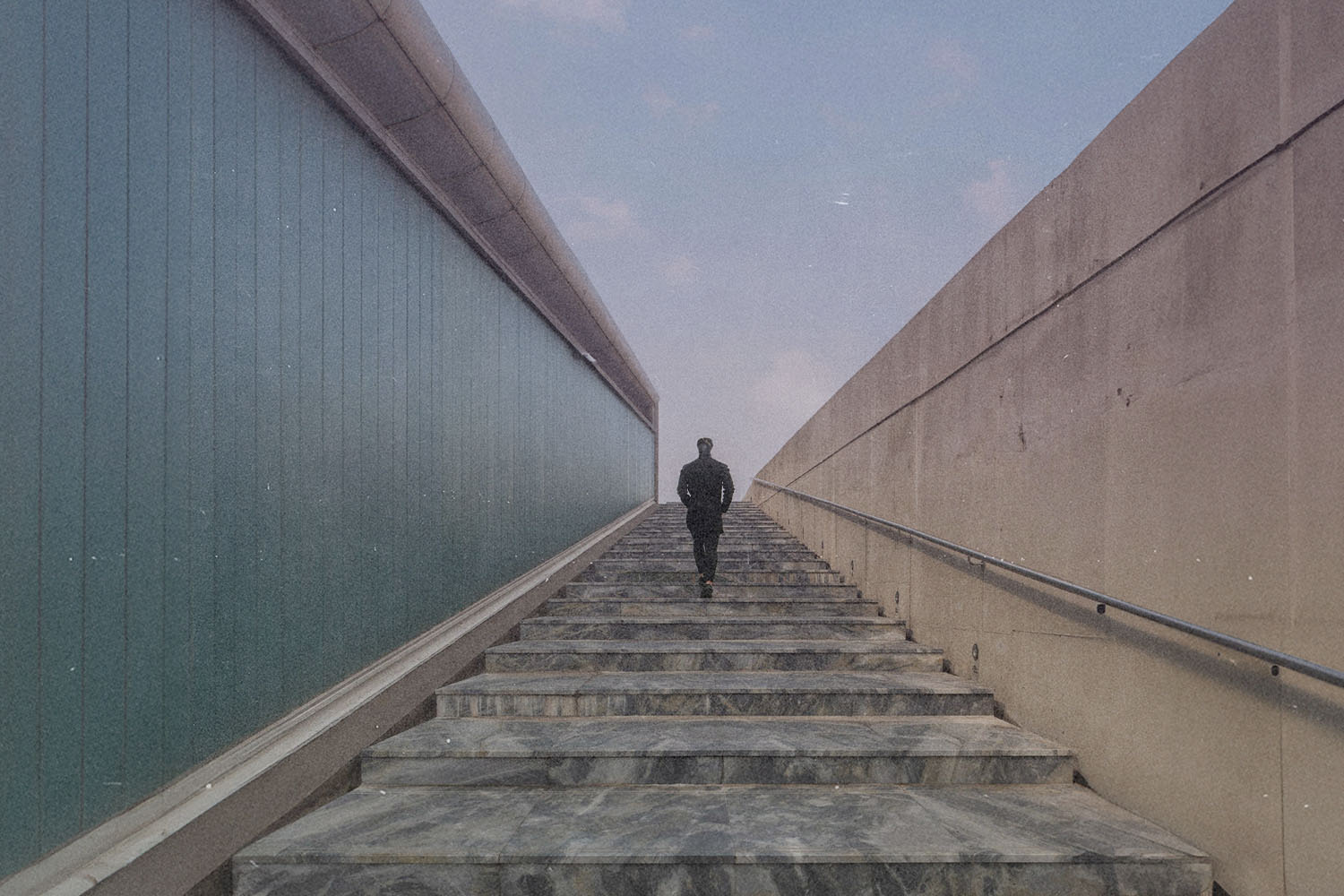 Person walking up outdoor stone stairs between tall walls