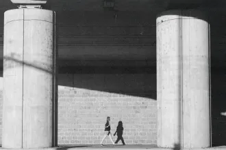 Woman walking through breezeway with two concrete pillars in view 