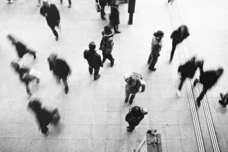 Black and white, blurred, aerial view of crowd of people walking 