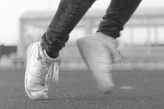Close-up of a person in motion wearing worn sneakers on an outdoor track