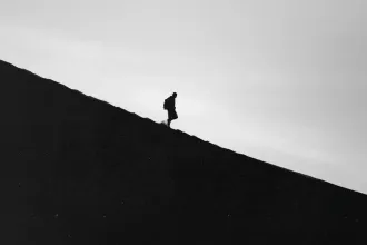 Black and white image of man walking down a steep slope