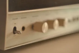 Close-up of a vintage audio receiver showing a metal power toggle switch and several blurred control knobs
