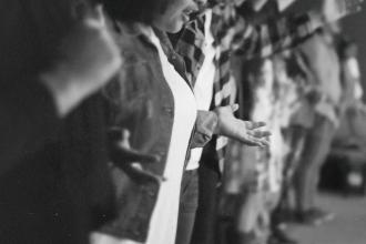 People standing in a row with their arms extended and hands open in a gesture of worship or prayer