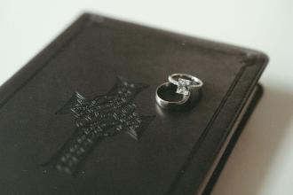 Wedding rings resting on top of a closed leather Bible embossed with a decorative cross