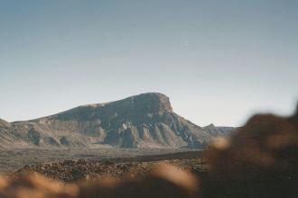 Large mesa standing in an open desert landscape under bright, cloudless skies