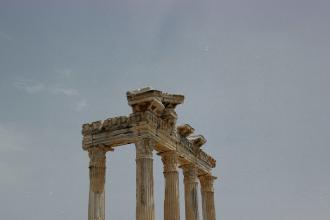 The upper portion of ancient stone columns stands against a pale sky, showcasing weathered classical architecture