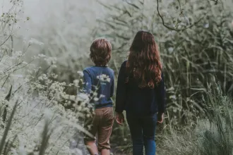 Two children walking along a path through tall greenery, symbolizing guiding Children of God with spiritual authority in a scroll‑driven world today.