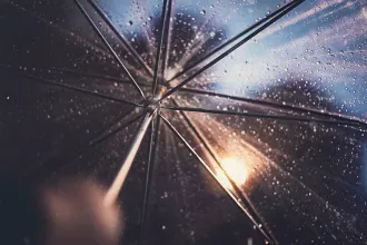 Looking through an umbrella at a rainy and sunny sky, showing us what it's like to protect your family with an umbrella of God's Grace