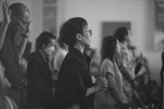 Crowd of people engaged in worship, with hands lifted and bodies turned toward the front