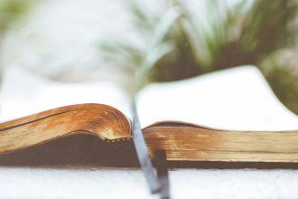 w-angle view of an open Bible with aged, textured pages and a dark ribbon bookmark