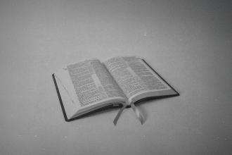 Open Bible resting on a flat surface with ribbon markers lying across the pages