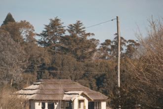 Cottage-style building at the edge of a wooded area with a power line overhead