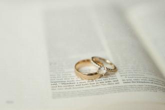 Gold wedding rings resting on an open Bible with the text softly blurred around them