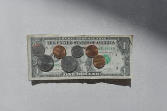 U.S. one-dollar bill laid flat with assorted coins arranged on top in natural light