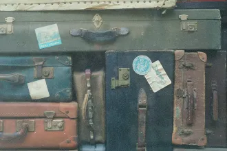 Collection of old-fashioned suitcases stacked tightly together, some decorated with vintage travel stickers