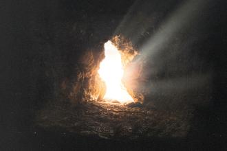 Sunlight streaming through the opening of a rocky cave, illuminating the stone floor with bright, warm rays