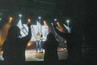 Worship band performing on stage with audience raising hands