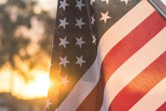 American flag waving outdoors with warm sunlight shining through at sunset
