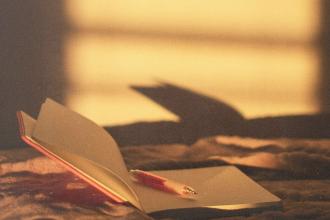 Open journal and pen resting on a blanket in warm golden sunlight