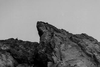 Jagged rock formation rising sharply against a clear sky in a black‑and‑white landscape