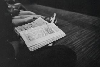Person holding an open Bible while seated in a quiet setting
