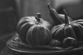 Black‑and‑white still life of assorted pumpkins and gourds arranged on a plate