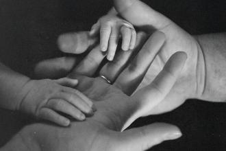 Close‑up of adult hands gently holding a baby’s hands