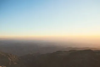 Sunrise casting warm light over distant mountain ridges