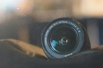 Close-up of a Canon EF‑S zoom lens resting on a dark fabric surface with blurred background lights