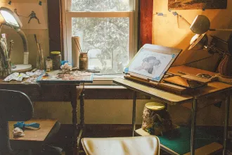 Cozy art studio with drawing desk, paints, and window light