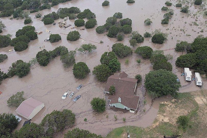 Aerial view of Kerrville, Texas flood damage with homes, vehicles, and trees submerged after heavy rain. Severe Texas flooding captured overhead.