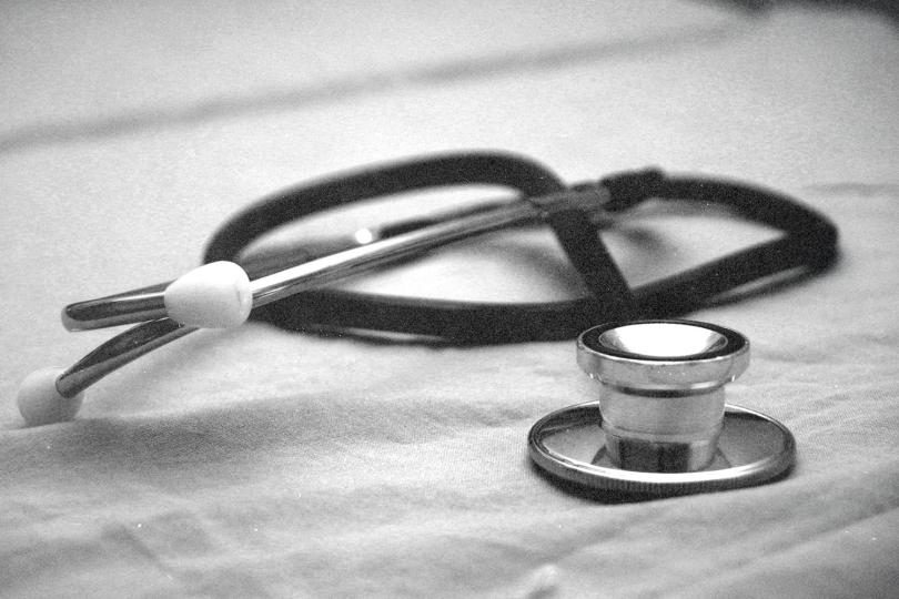 Stethoscope resting on a fabric surface in a softly lit black‑and‑white setting