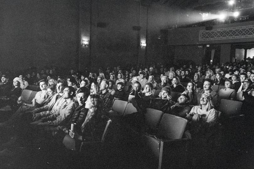 Large audience seated in a theater watching a performance or presentation