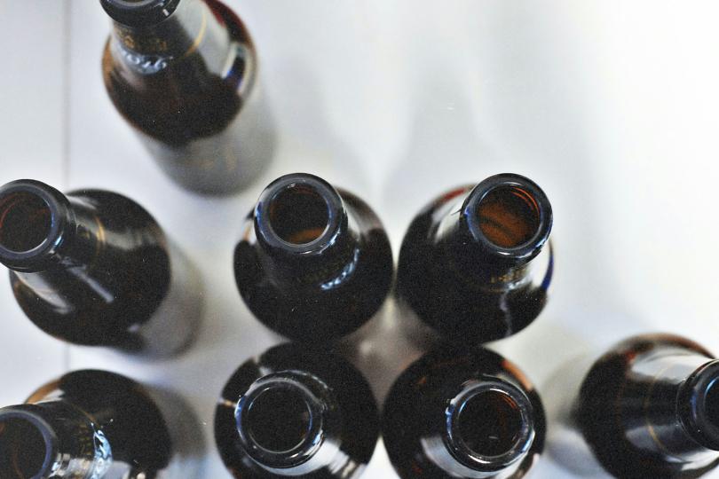 Group of dark glass bottles arranged closely together viewed from above