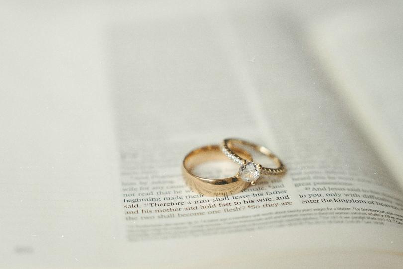 Gold wedding rings resting on an open Bible with the text softly blurred around them