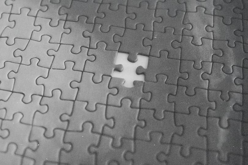 Black-and-white puzzle with one central piece missing, revealing an empty white space